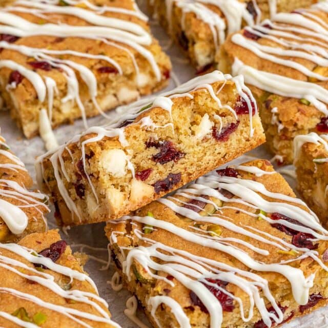 Cranberry Pistachio Blondies with white chocolate drizzle sliced on parchment