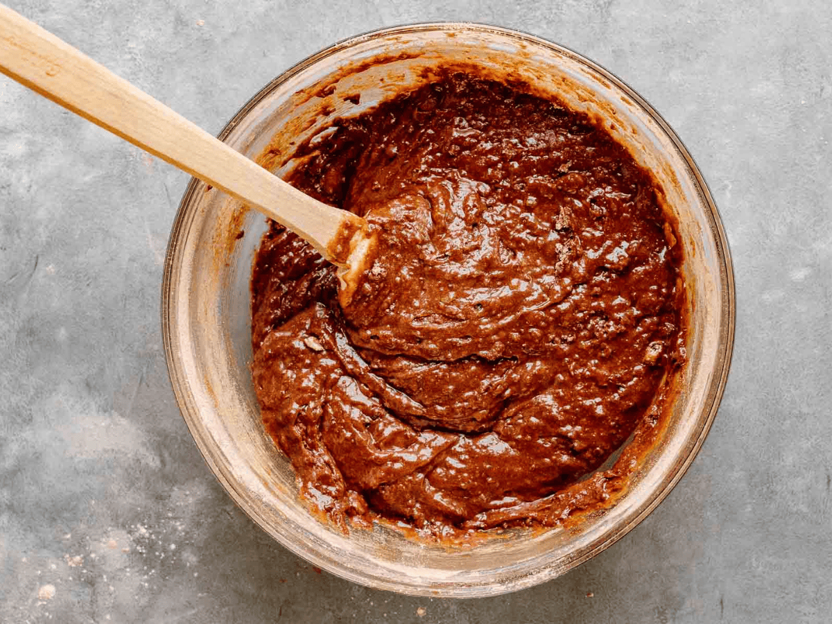 chocolate batter in a glass bowl with wooden spoon