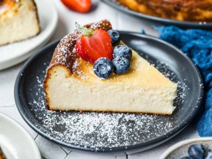 Slice of cheesecake on a plate with powdered sugar topping