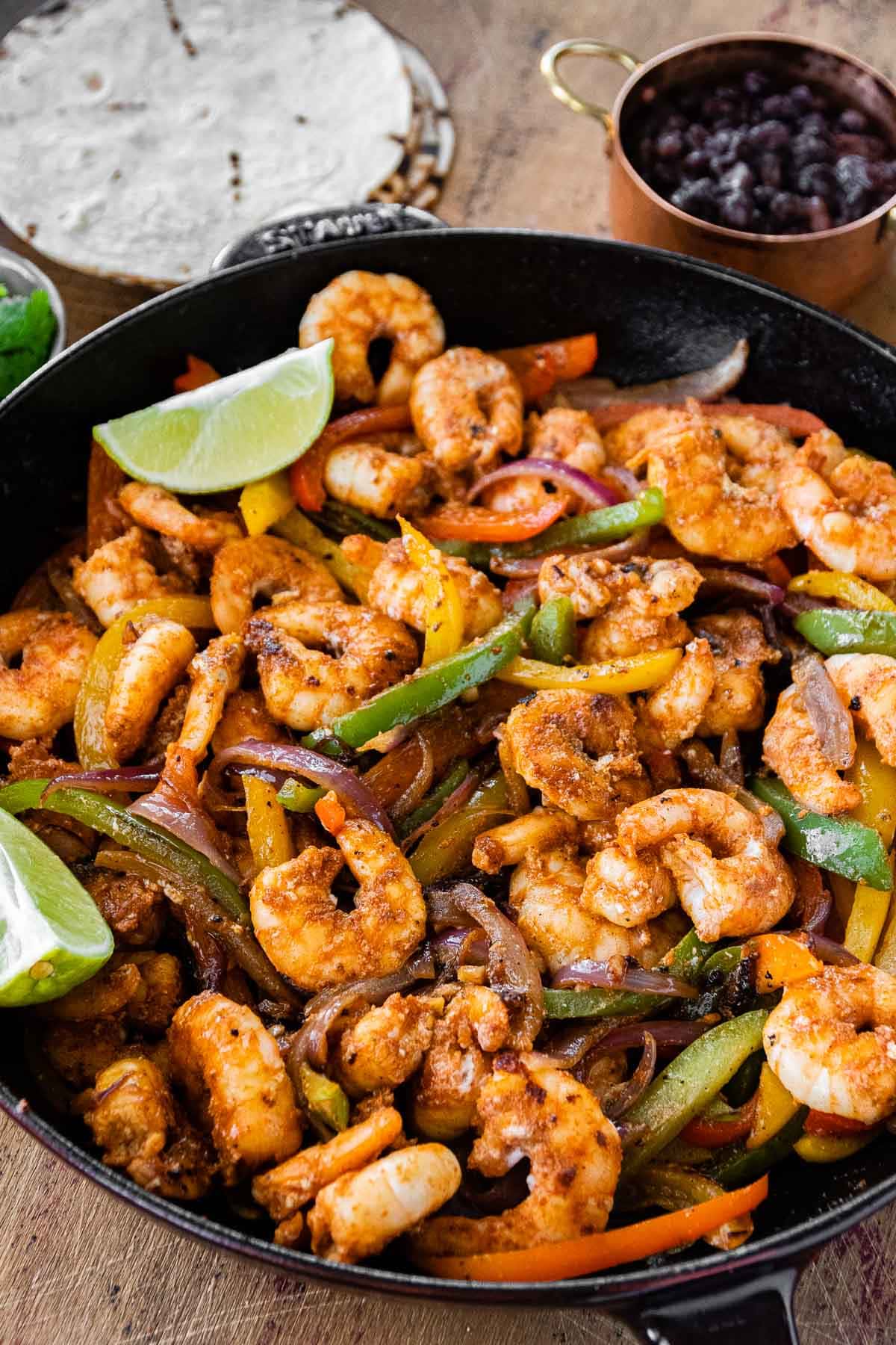 Shrimp Fajitas finished in skillet with bowl of rice next to it at the top