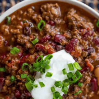 chili in a bowl topped with sour cream and green onion
