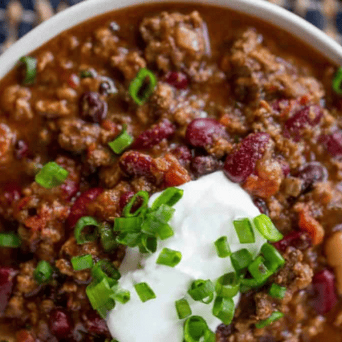 chili in a bowl topped with sour cream and green onion