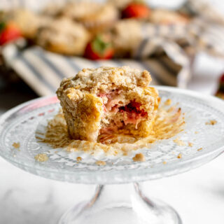 Strawberry Crumb Muffin on small cake plate with wrapper pulled down and bite taken out