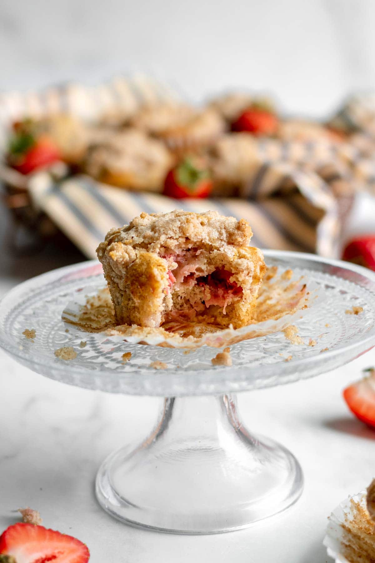 Strawberry Crumb Muffin on small cake plate with wrapper pulled down and bite taken out