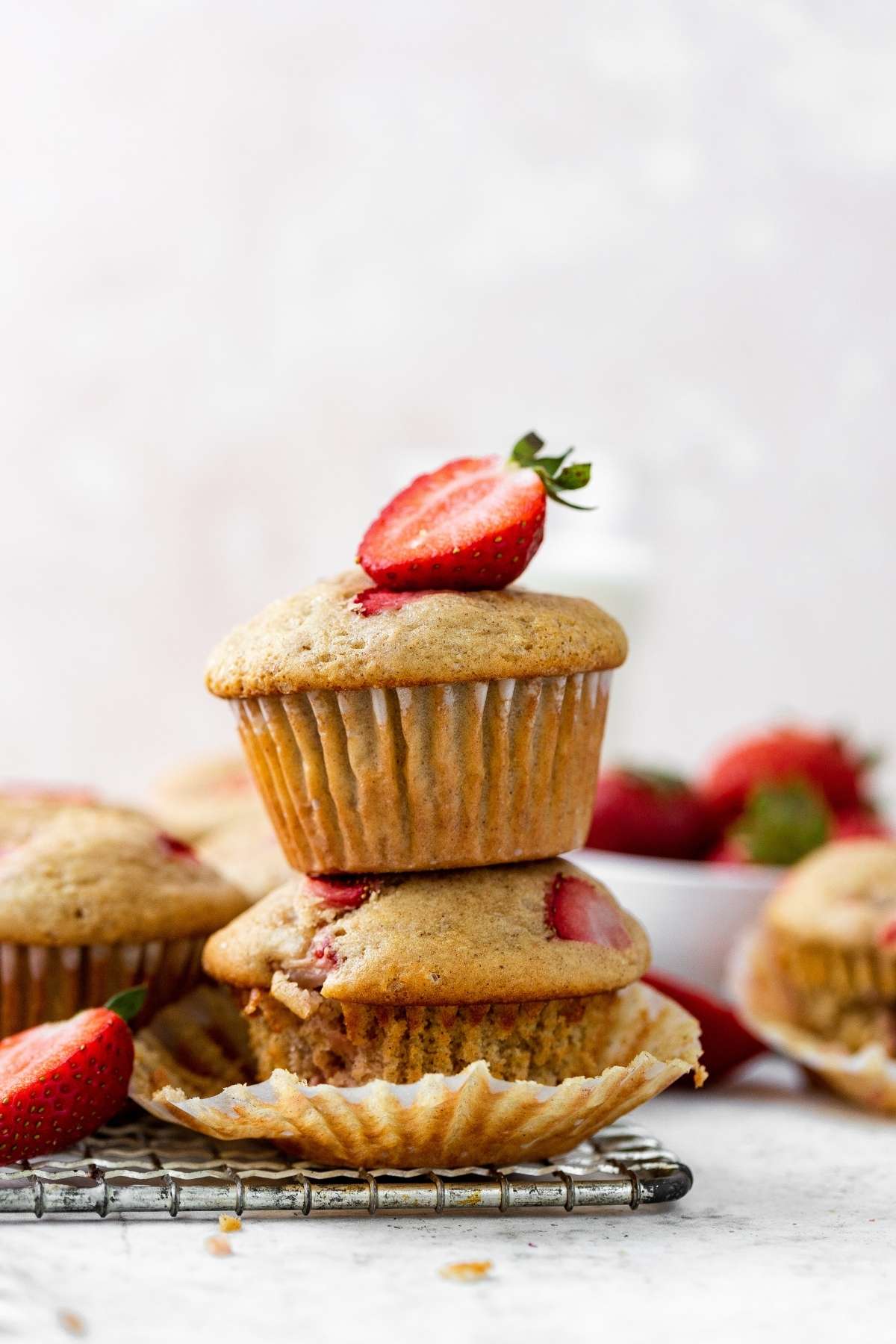 Strawberry Muffins stacked on cooling rack with fresh strawberry garnish