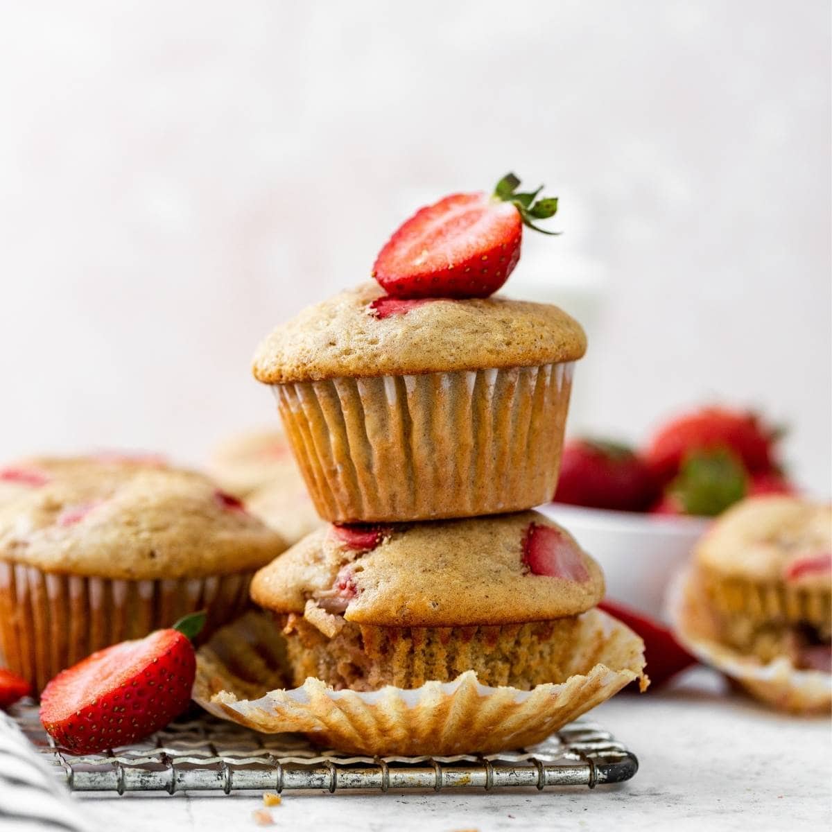 Strawberry Muffins stacked on cooling rack with fresh strawberry garnish