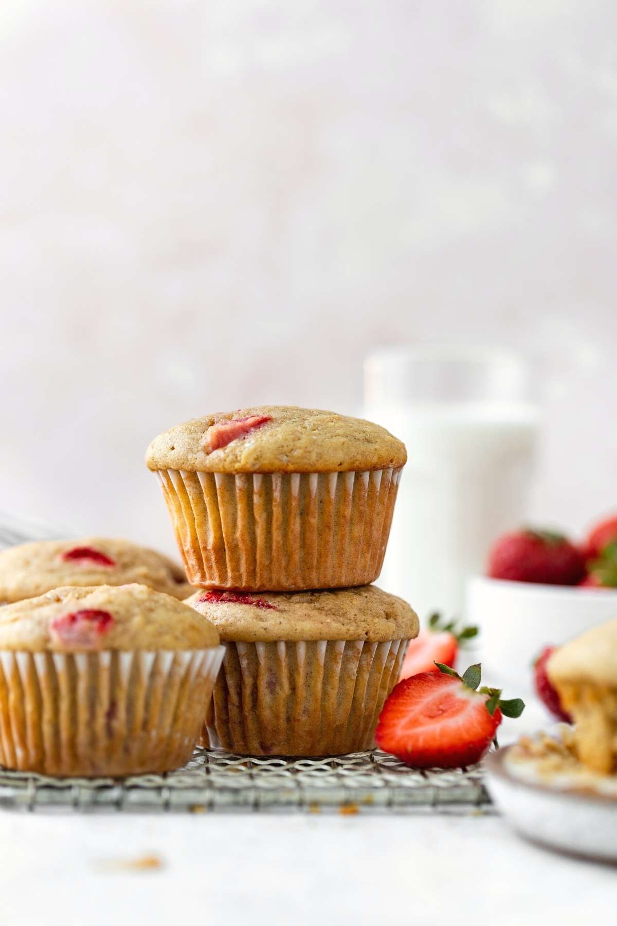 Strawberry Muffins stacked on cooling rack with fresh strawberry garnish