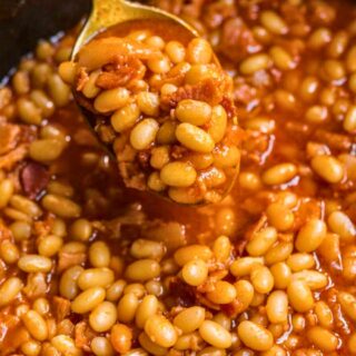 close up of portion on spoon over pot of cooked pork and beans