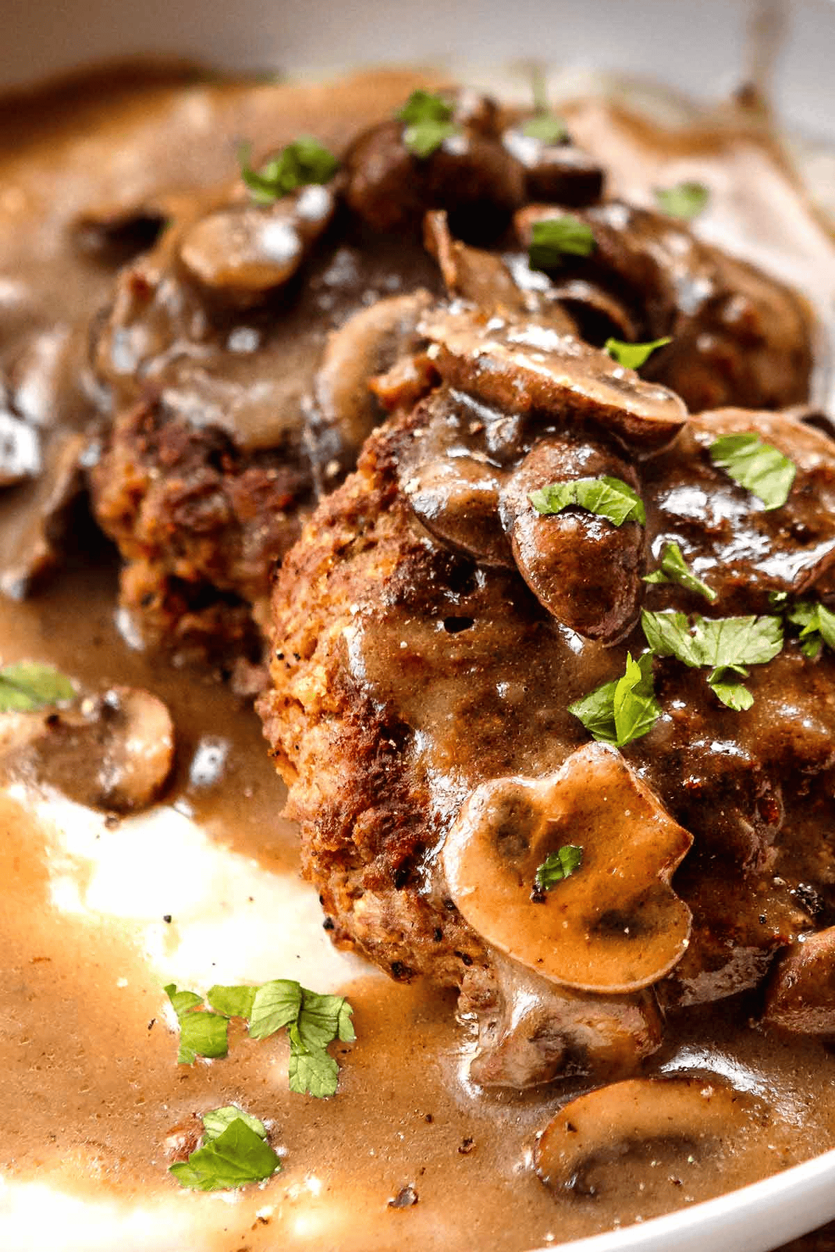 Close up photo of mushroom gravy poured over beef patties