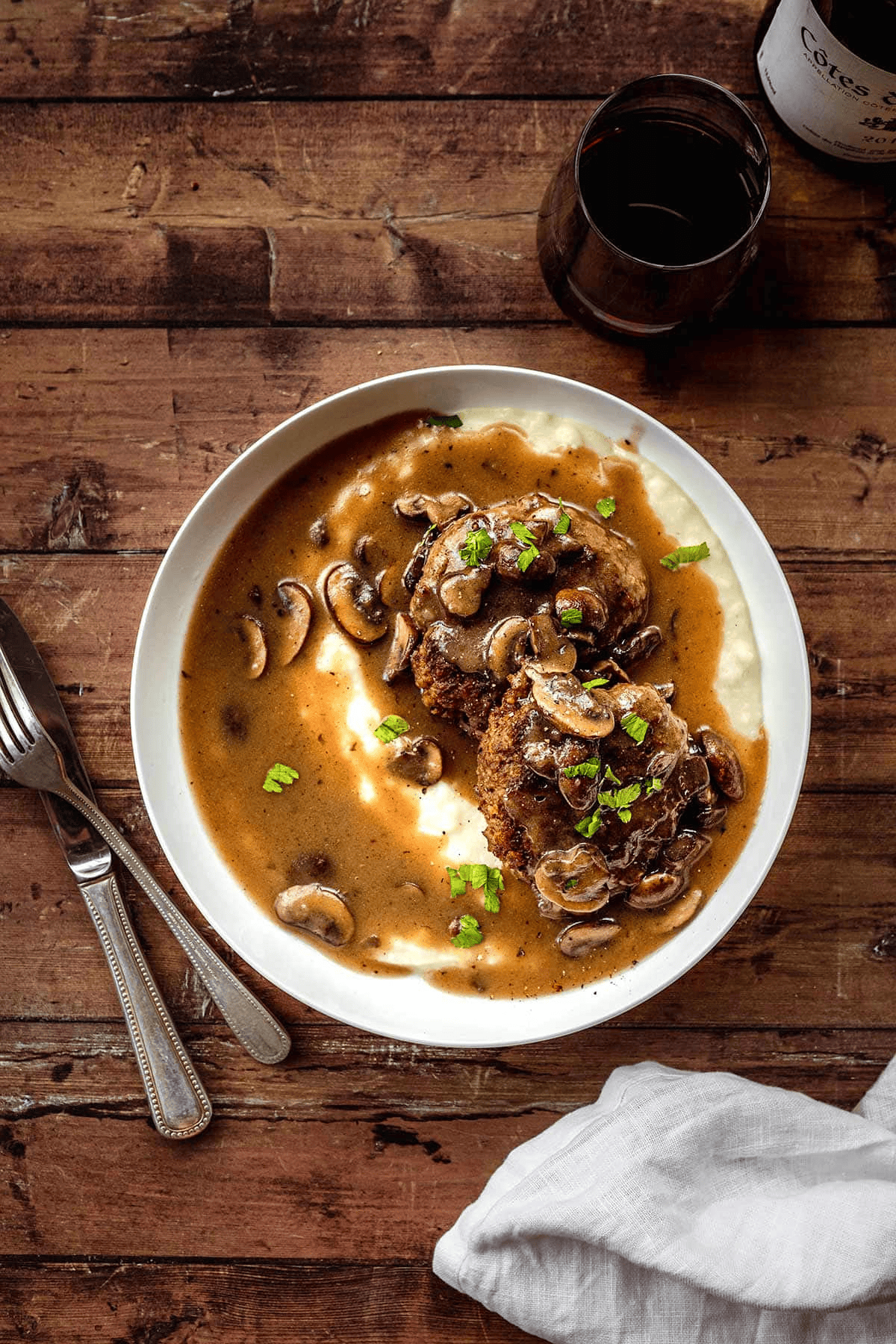 Steak dinner in a white serving bowl with fork and knife on the side