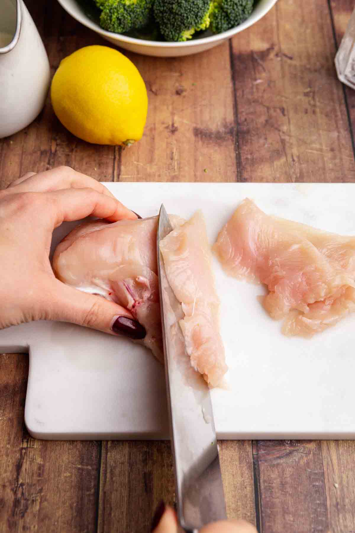 Lemon Parmesan Chicken Skillet cutting raw chicken breasts on cutting board