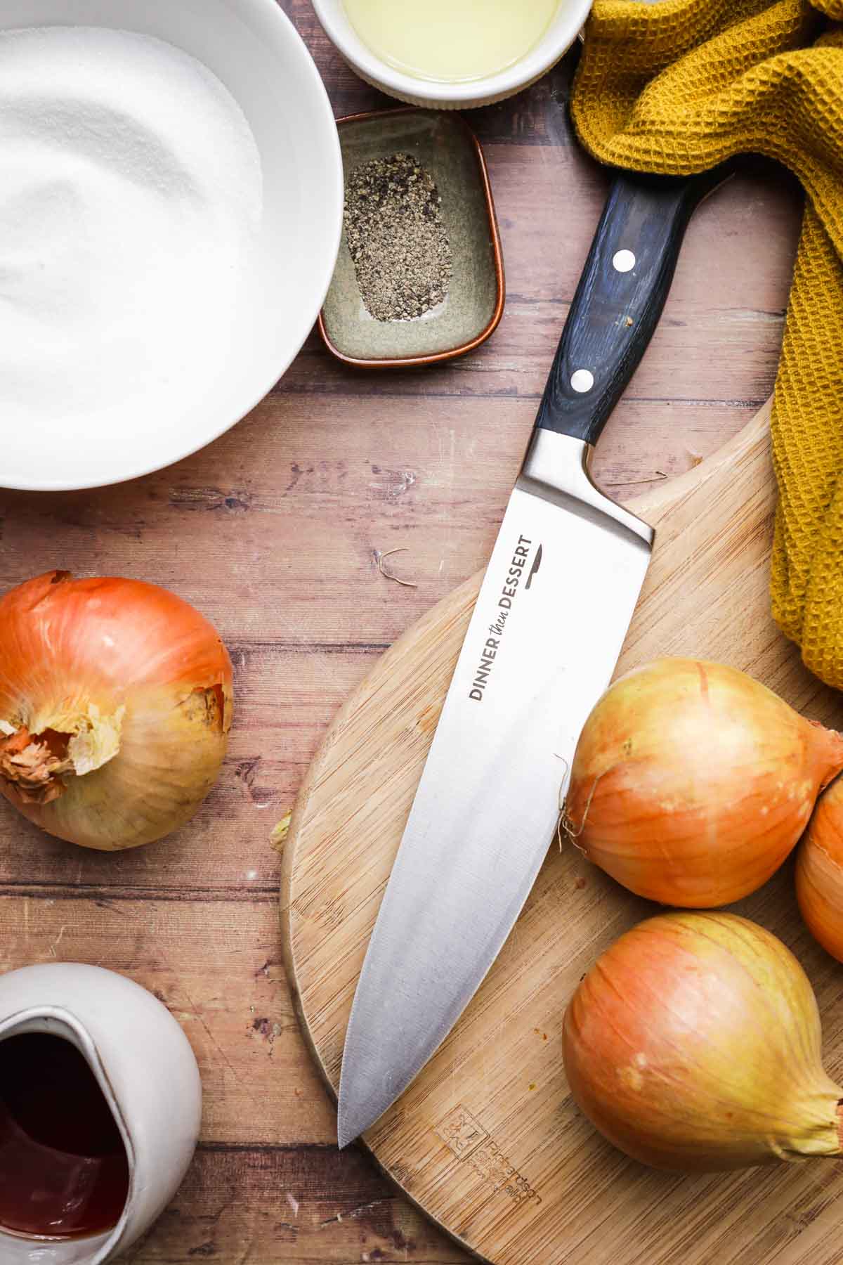 Onion Jam Ingredients spread out and chefs knife in middle next to uncut onions