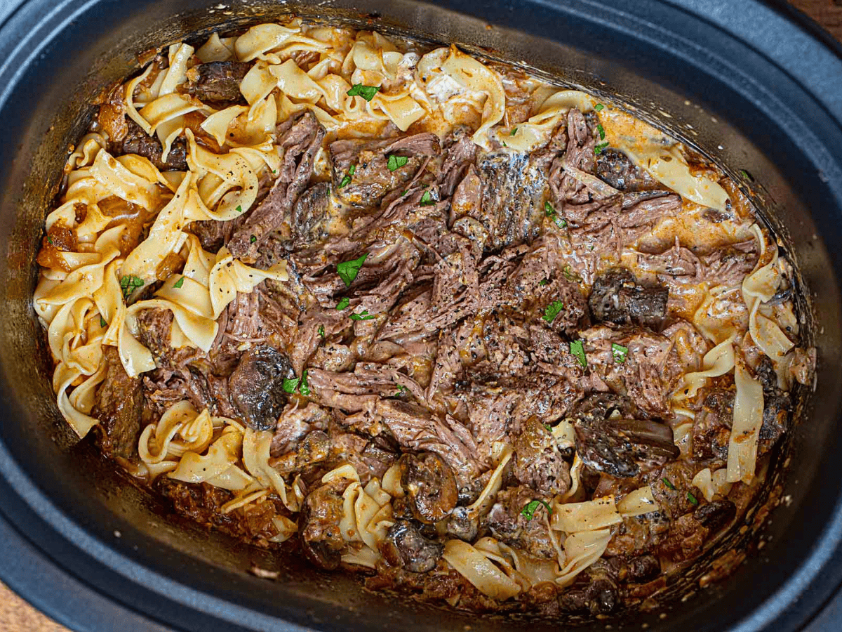 noodles, beef, sour cream, and sauce in a pot mixed together
