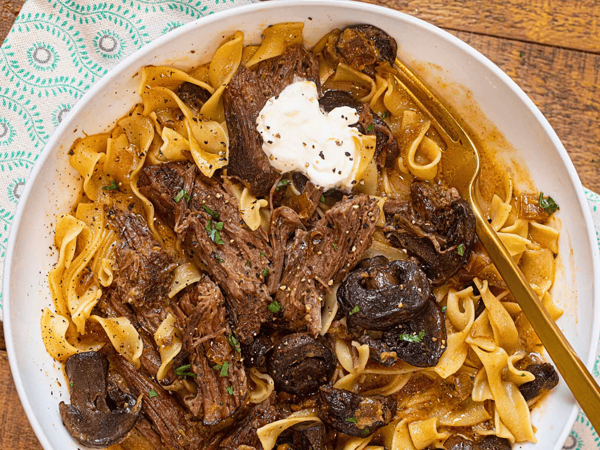 noodles, beef, sour cream, and sauce on a white plate with fork