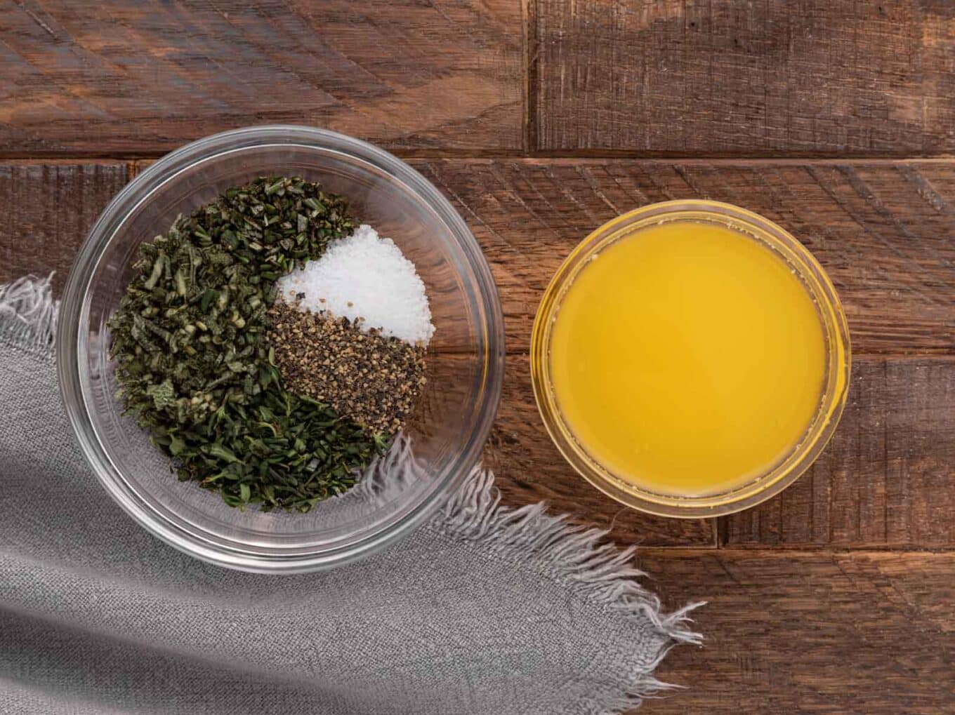 bowl of melted butter at top and bowl of herbs