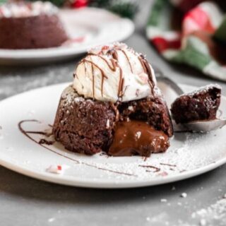 Cake on a white plate with vanilla ice cream on top.