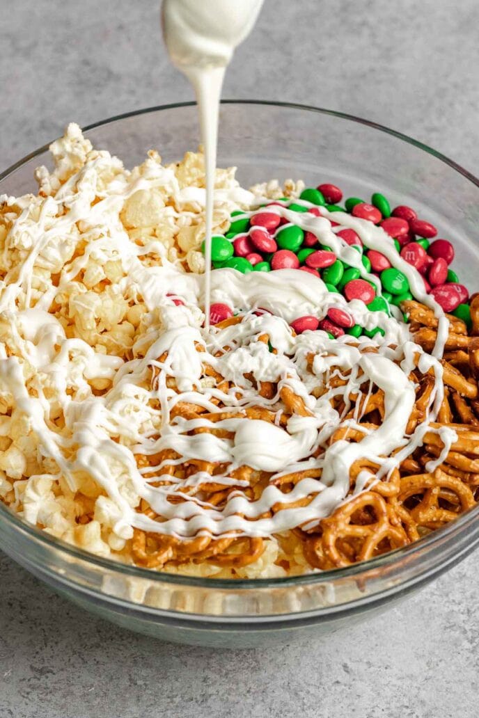 Christmas Popcorn Crunch ingredients in Bowl with white chocolate drizzle on top
