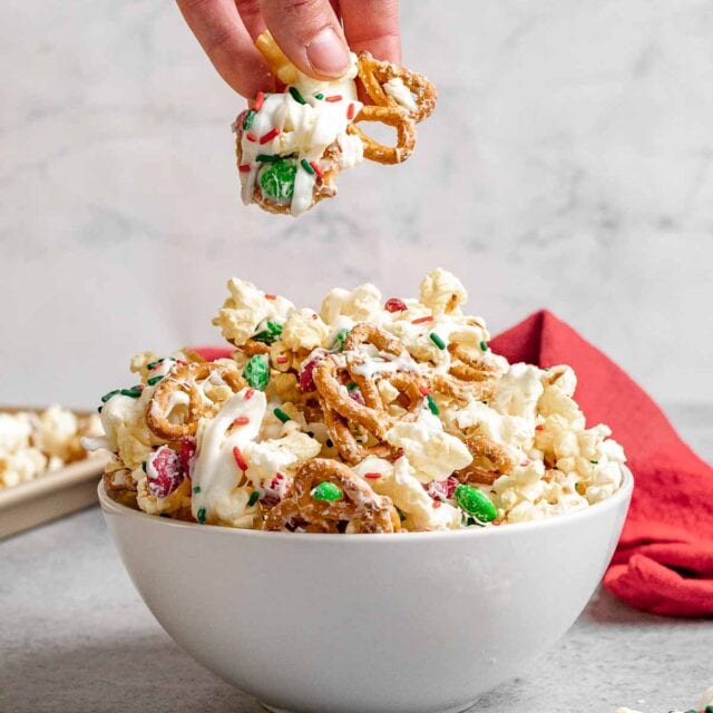 Christmas Popcorn Crunch in Bowl with hand holding portion