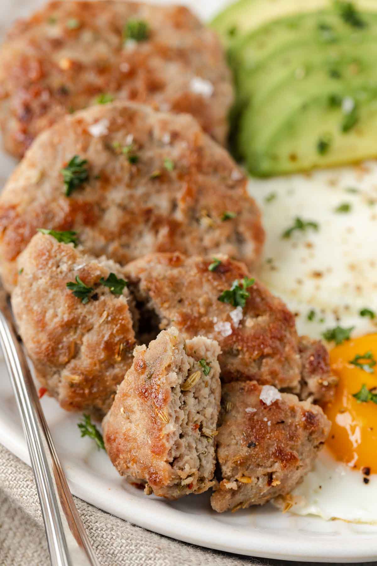 closeup of plate of Maple Breakfast sausage with 2 fried eggs and slices of avocado