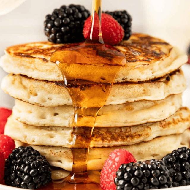 Cooked ingredients on a plate with berries and syrup being poured on top