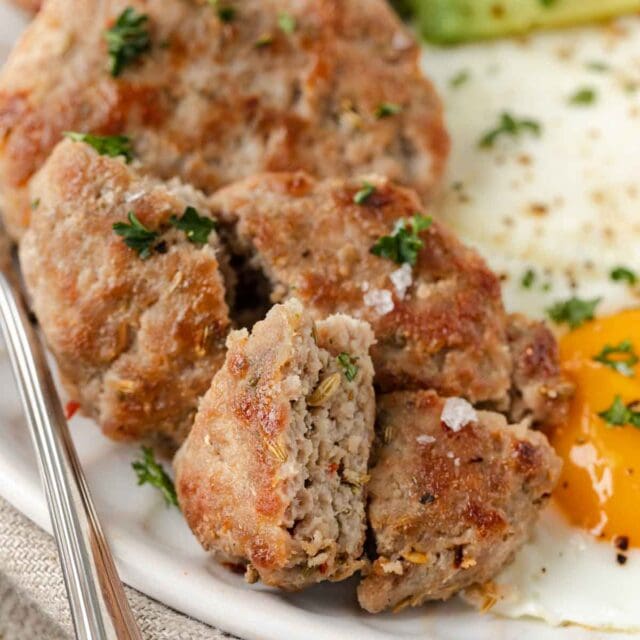 closeup of plate of Maple Breakfast sausage with 2 fried eggs and slices of avocado