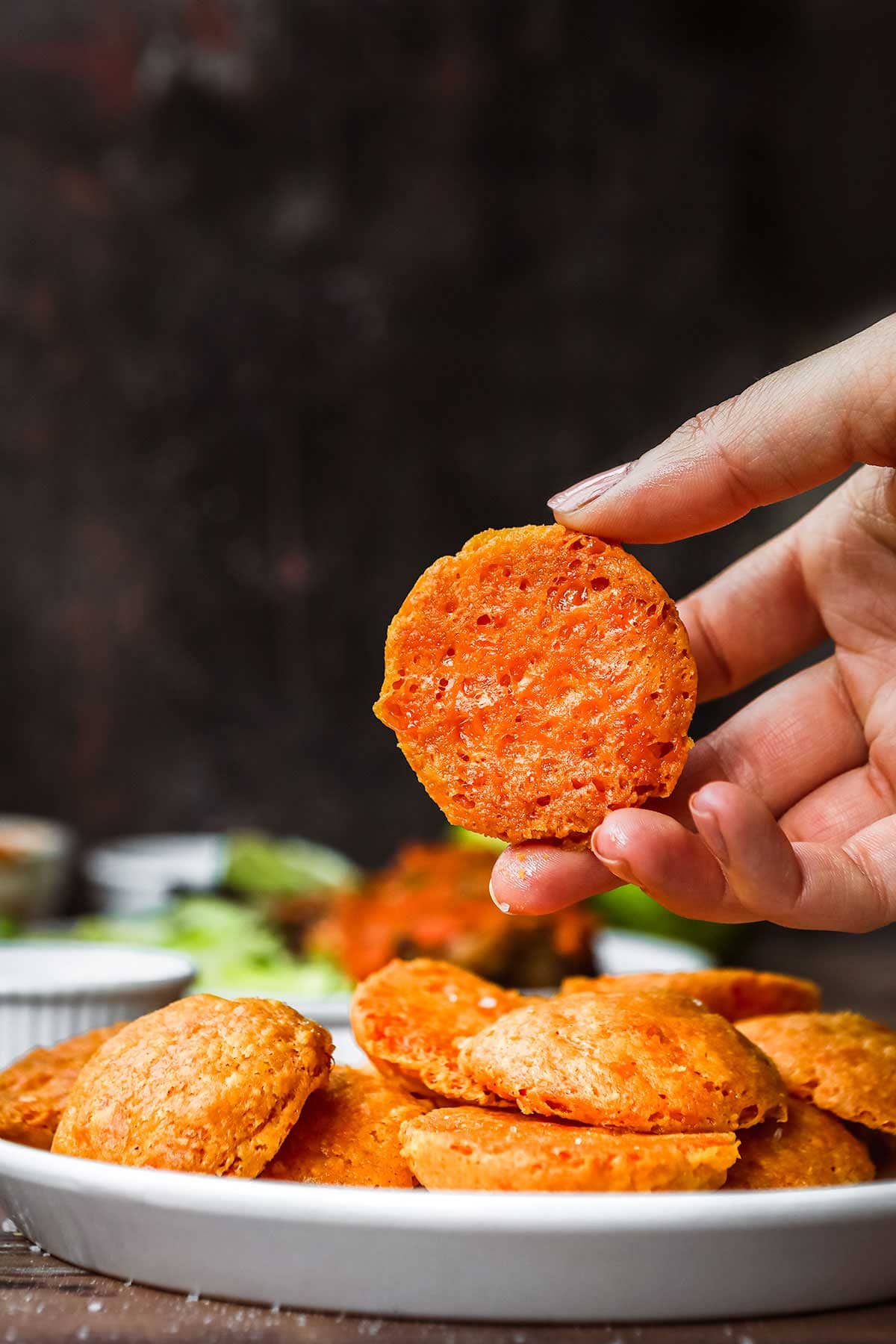 Sharp Cheddar Crackers on serving plate with hand picking one up