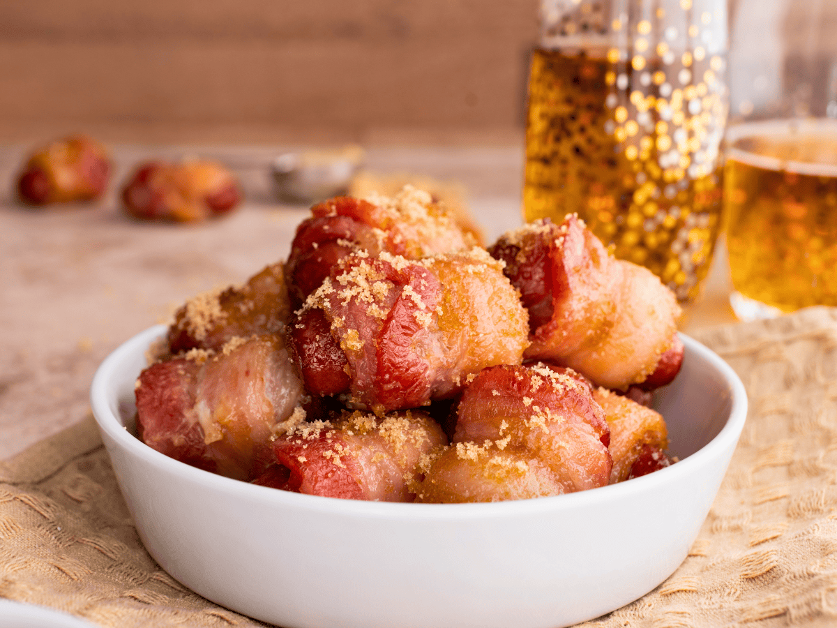 mini hot dogs wrapped in caramelized bacon in a white bowl