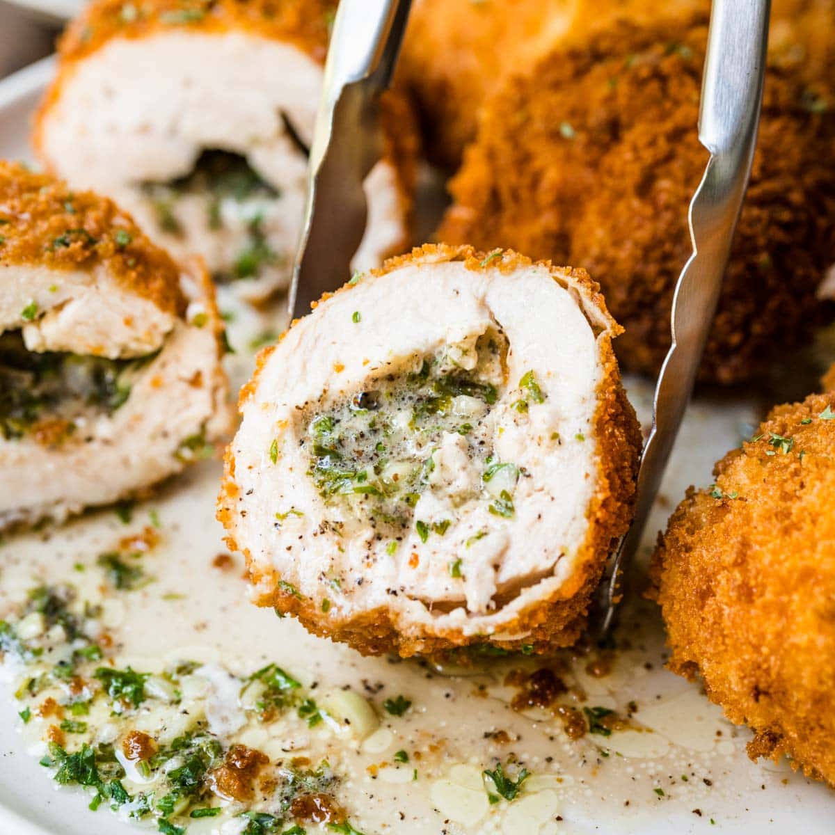 Chicken Kiev close up cut in half held by tongs