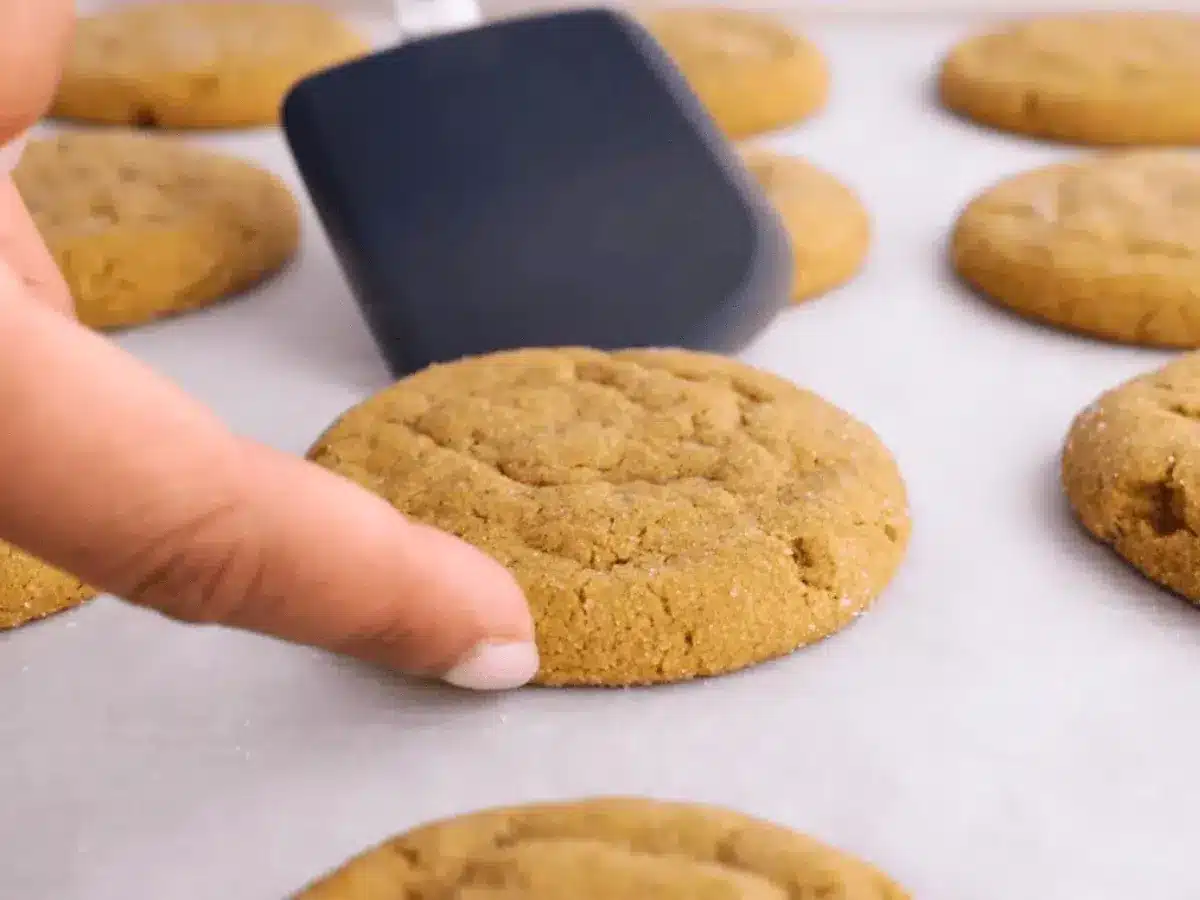 Cookie on baking sheet with spatula and finger