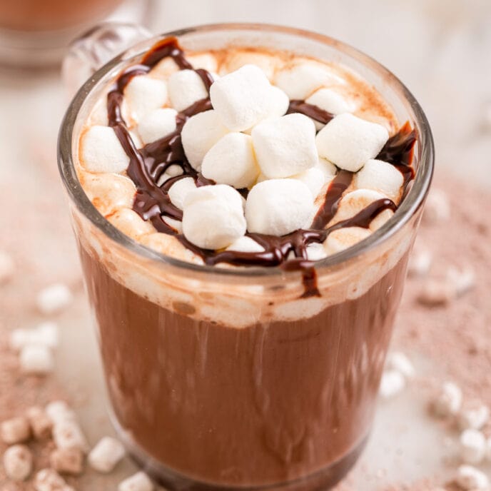 Hot Chocolate Mix Prepared in Glass Mug with Marshmallows and Chocolate Sauce