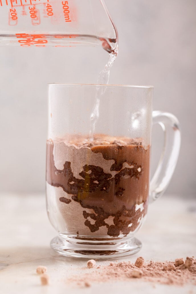 Hot Chocolate Mix ingredients in glass mug with water unmixed