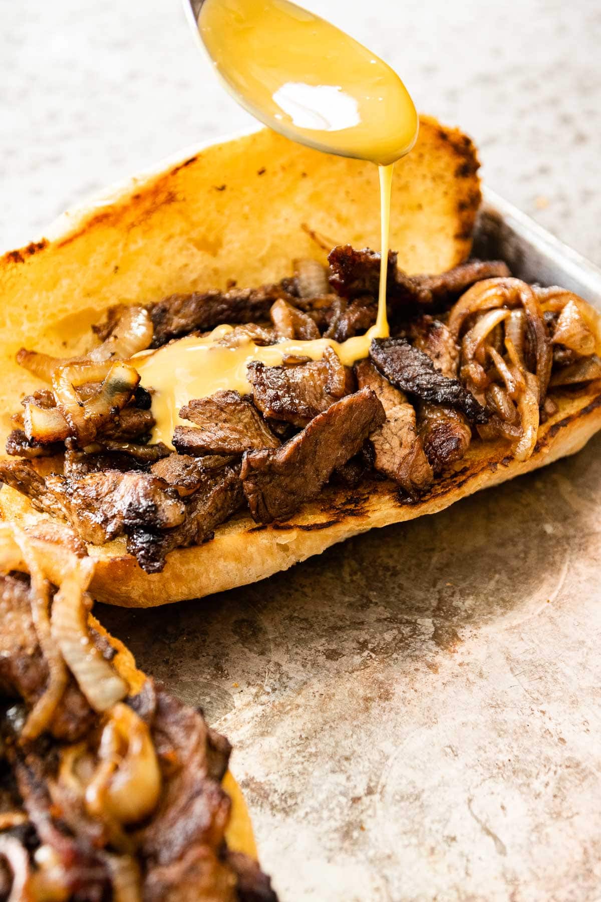 Philly Cheesesteak on serving plate with cheese sauce