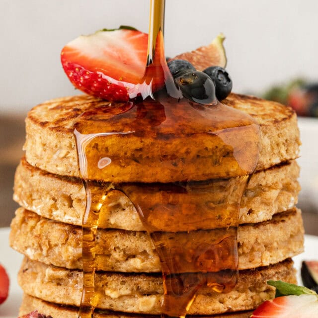 Syrup being poured on a stack of griddle cakes.