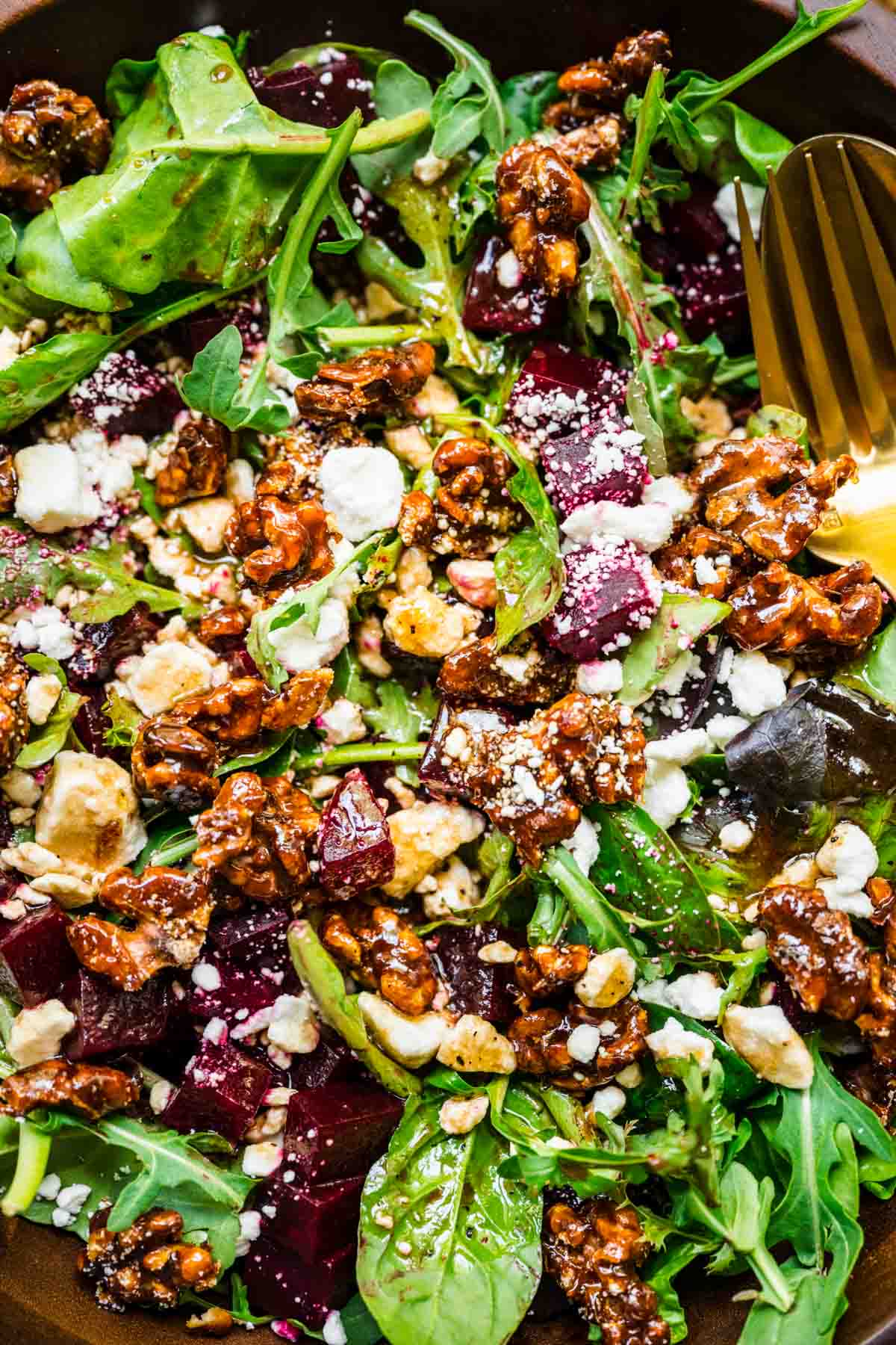 Beet and Goat Cheese Salad in wooden bowl with fork and spoon close up