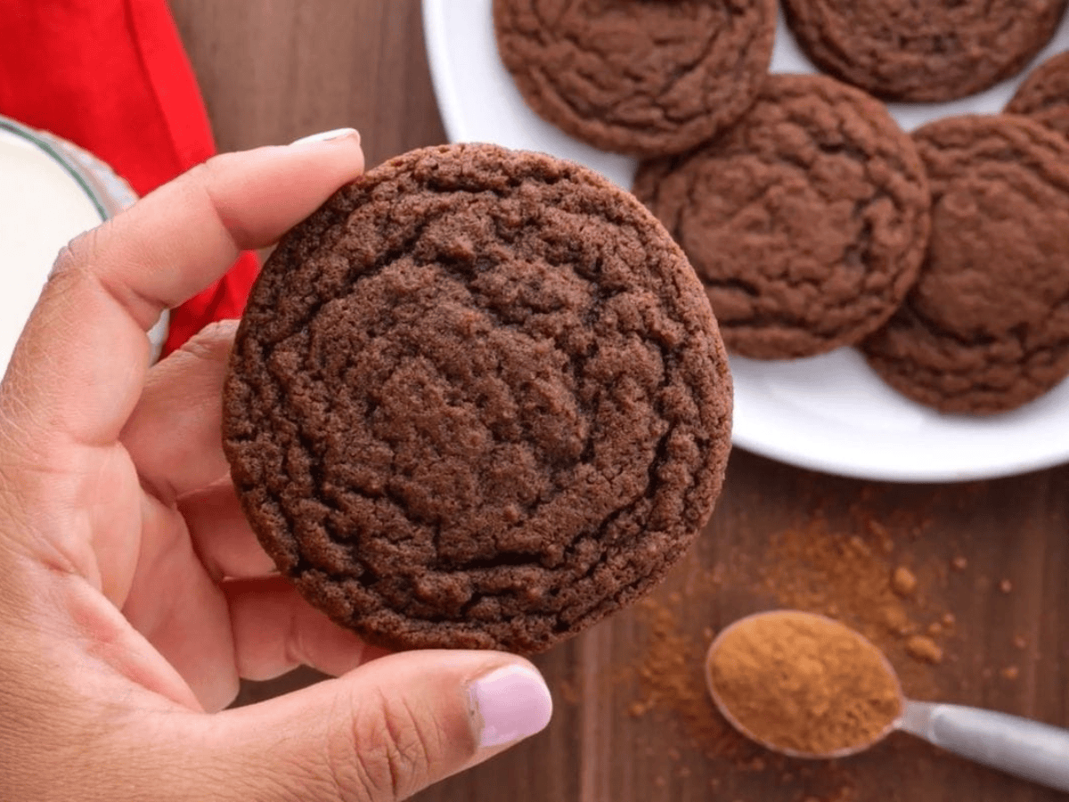 hand holding cookies with plate of cookies in the background