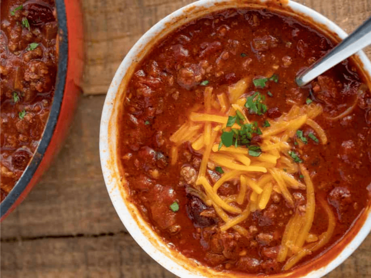 chili topped with cheese in bowl with spoon
