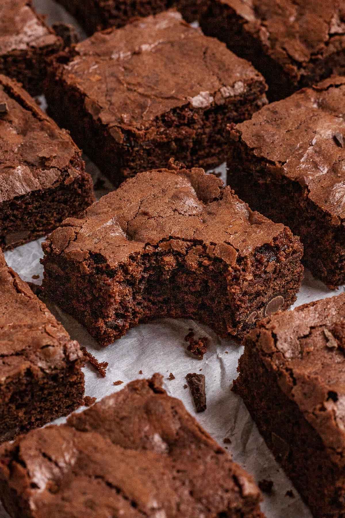 Double Chocolate Brownies cut on parchment paper with center brownie has bite taken out