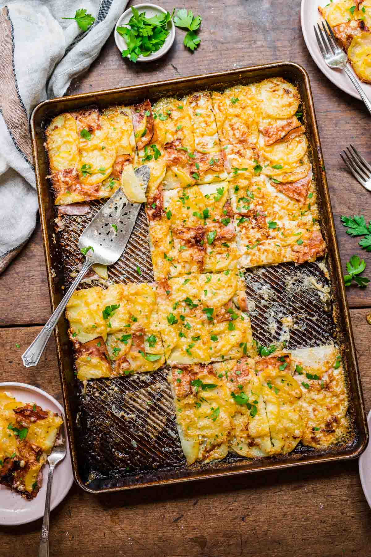 Sheet Pan Ham and Swiss Scalloped Potatoes cut pieces on pan with spatula