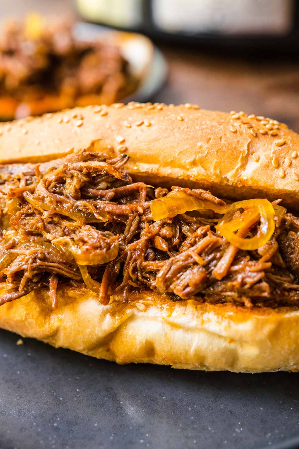 Slow Cooker Shredded Beef filling in hoagie roll on plate