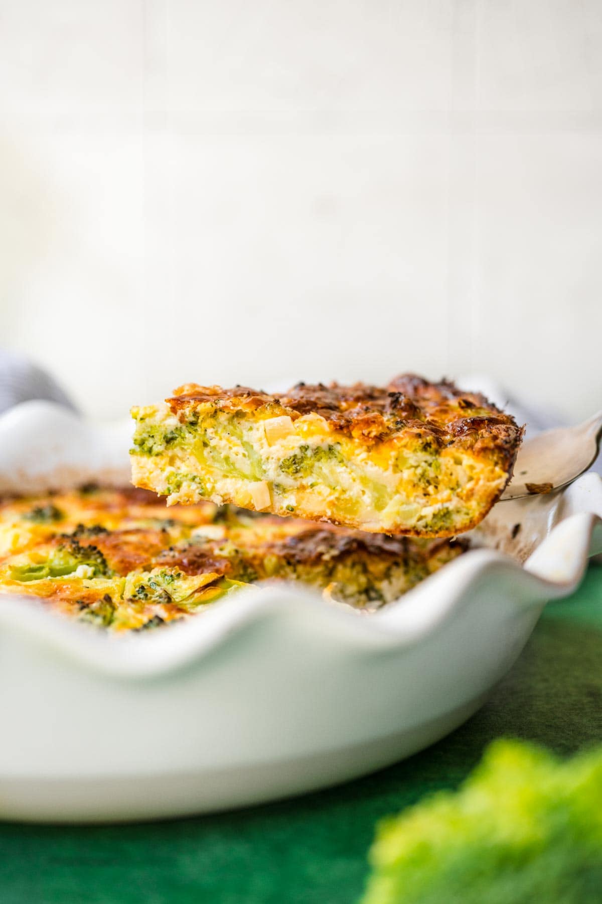 Broccoli Pie baked in pie dish side view with slice on spatula