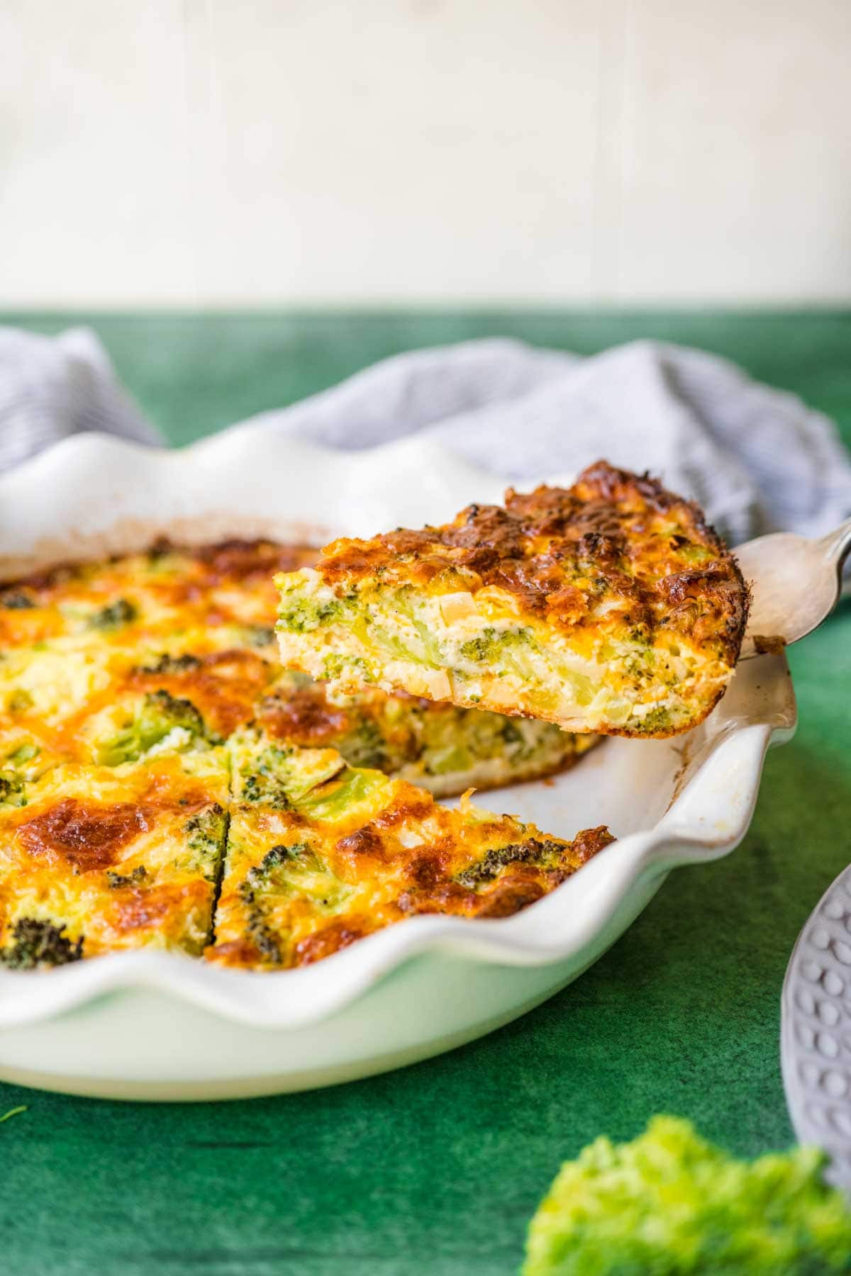 Broccoli Pie baked in pie dish side view with slice on spatula