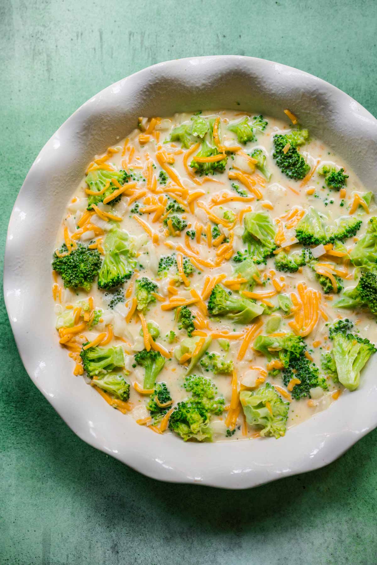 Broccoli Pie ingredients with broccoli uncooked in pie dish