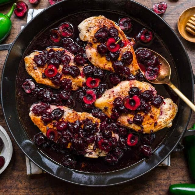 Chicken topped with cherry sauce in a pan