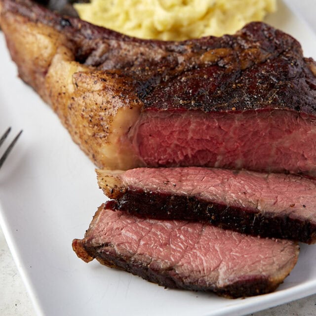 Steak on dinner plate, sliced and medium rare.