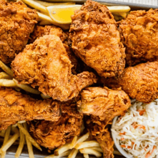 Multiple pieces of fried chicken with fries and coleslaw