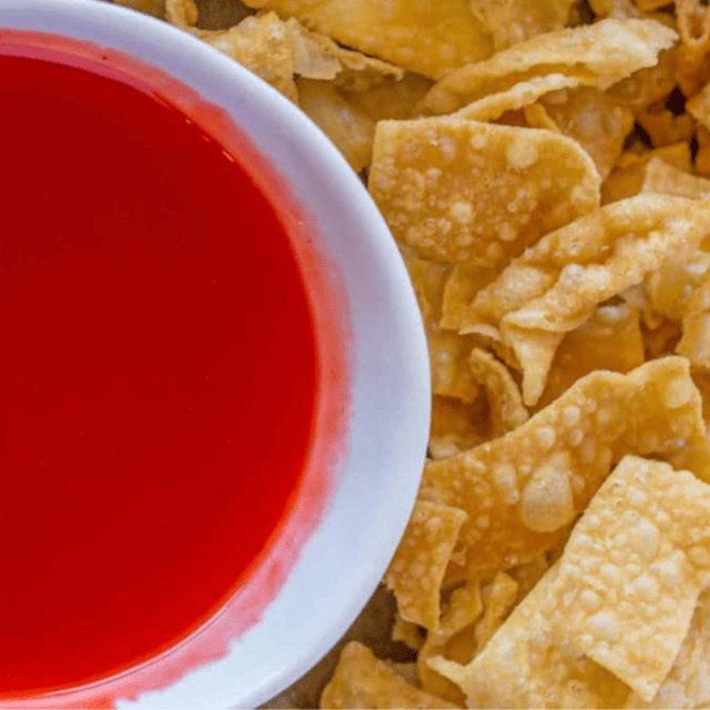 wontons on a side of a bowl of dipping sauce