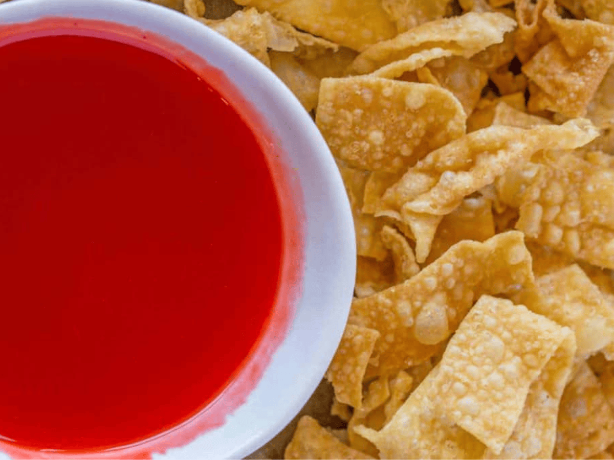wontons on a side of a bowl of dipping sauce