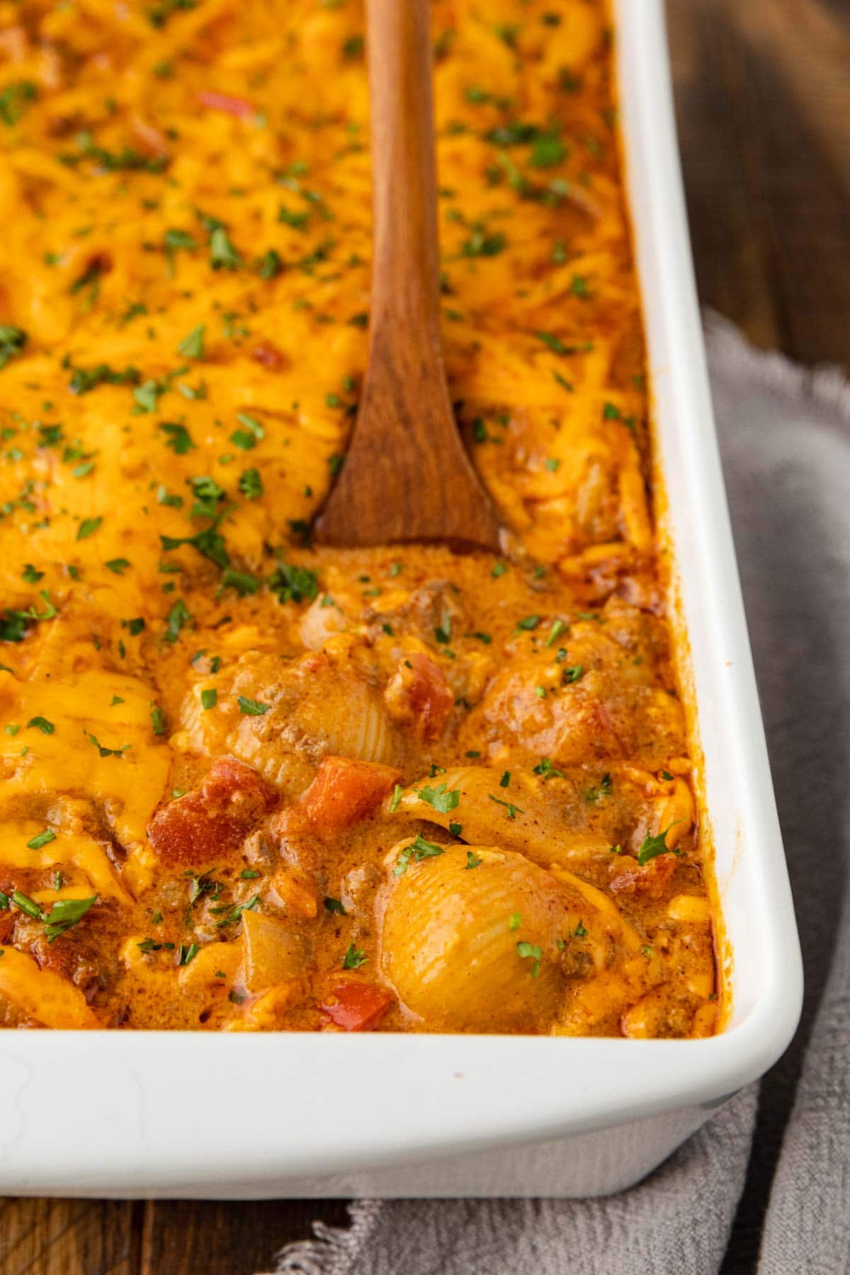 Tex Mex Cheesy Beef Pasta in baking dish baked close up with wooden spoon