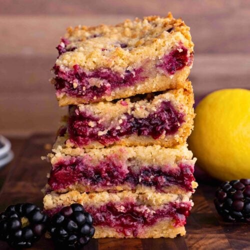 stack of baked bars with lemon and blackberries around it