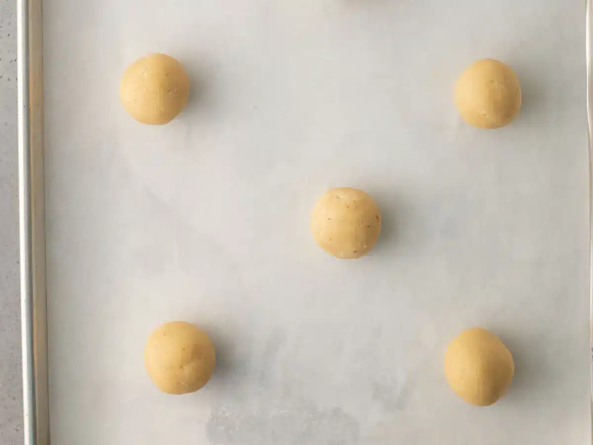 Balls of dough on parchment lined baking tray.